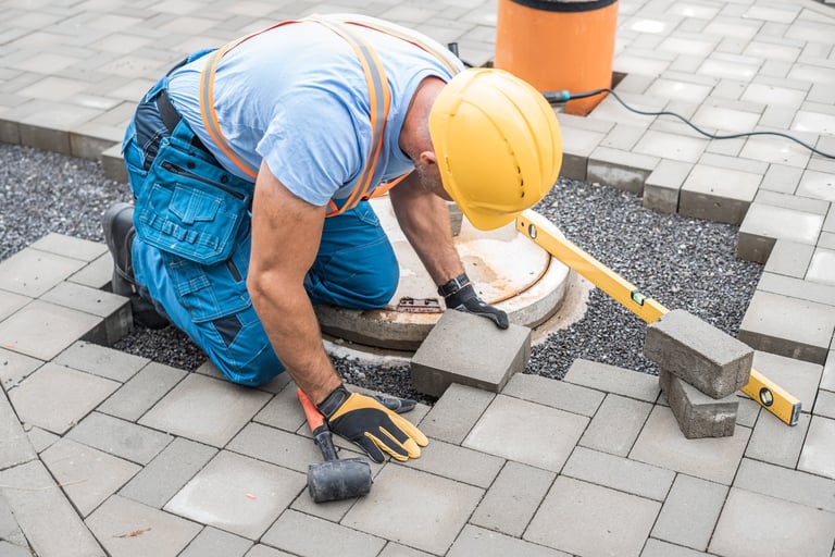 Worker laying interlocking paving stones for walkway