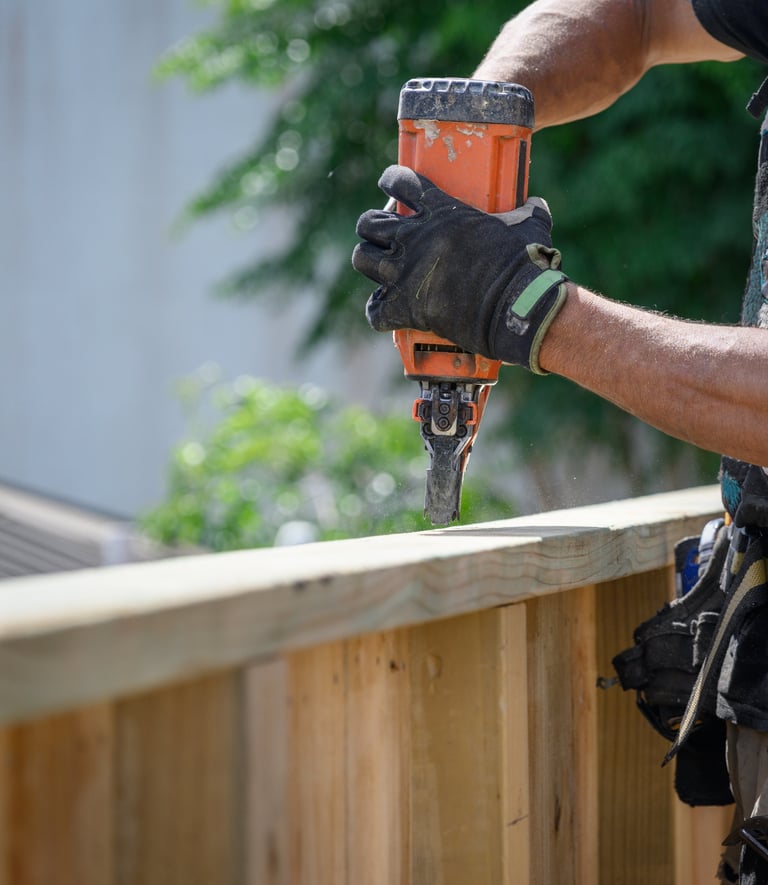 Builder working on fence with nail gun