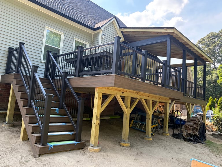 Elevated house deck with brown wooden stairs, metal railings, and yellow support posts underneath