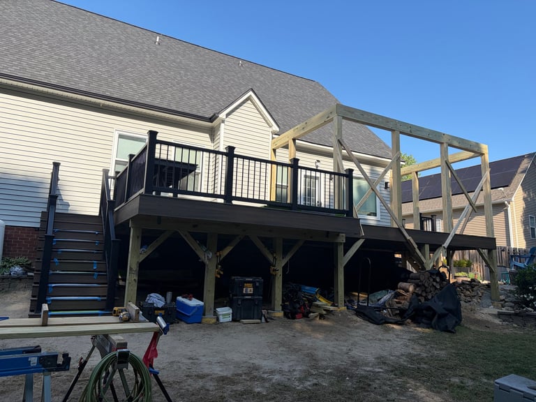 Residential deck under construction with black railings, wooden support structure, and storage underneath